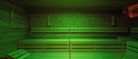 Una sala de sauna con bancos de madera y techo iluminado en verde.