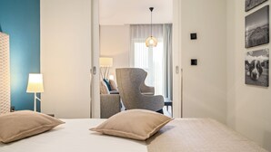 A hotel room with a bed, two pillows, a chair, a lamp, and a wall with pictures. - Ostseestuv – 5-Star Vacation Rental Between the Baltic Sea and the Bodden (Wustrow)