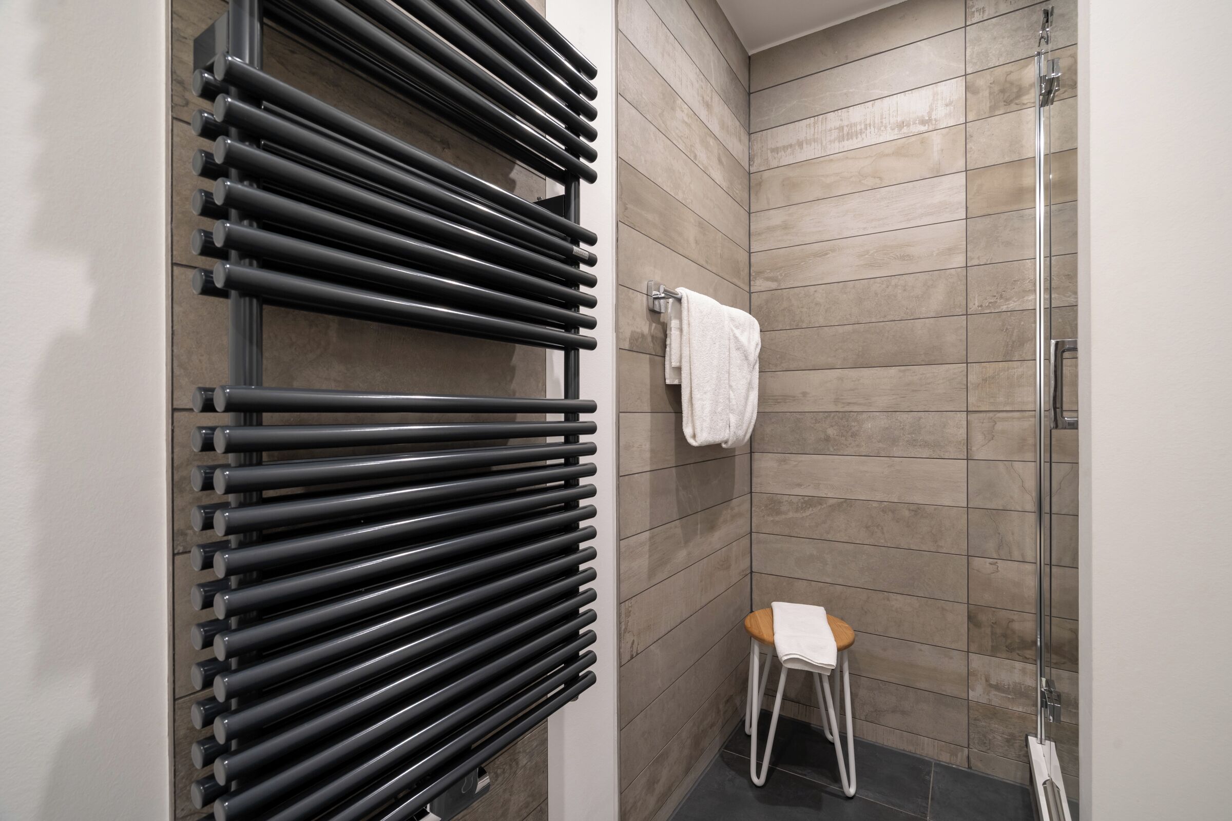 Une salle de bain équipée d’un porte-serviettes, d’un petit tabouret et d’un espace douche.