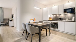 A modern kitchen with a dining area, featuring a built-in oven, microwave, and a dining table with chairs. - Ostseestuv – 5-Star Vacation Rental Between the Baltic Sea and the Bodden (Wustrow)