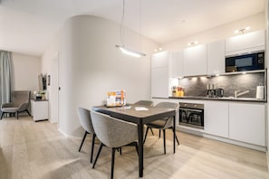 A modern kitchen with a dining area, featuring a built-in oven, microwave, and a dining table with chairs.