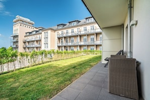 A multi-story residential building with balconies, a grassy courtyard, and a paved walkway.