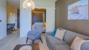 Ein modernes Wohnzimmer mit einem grauen Sofa, einem blauen Sessel und einem Holztisch.