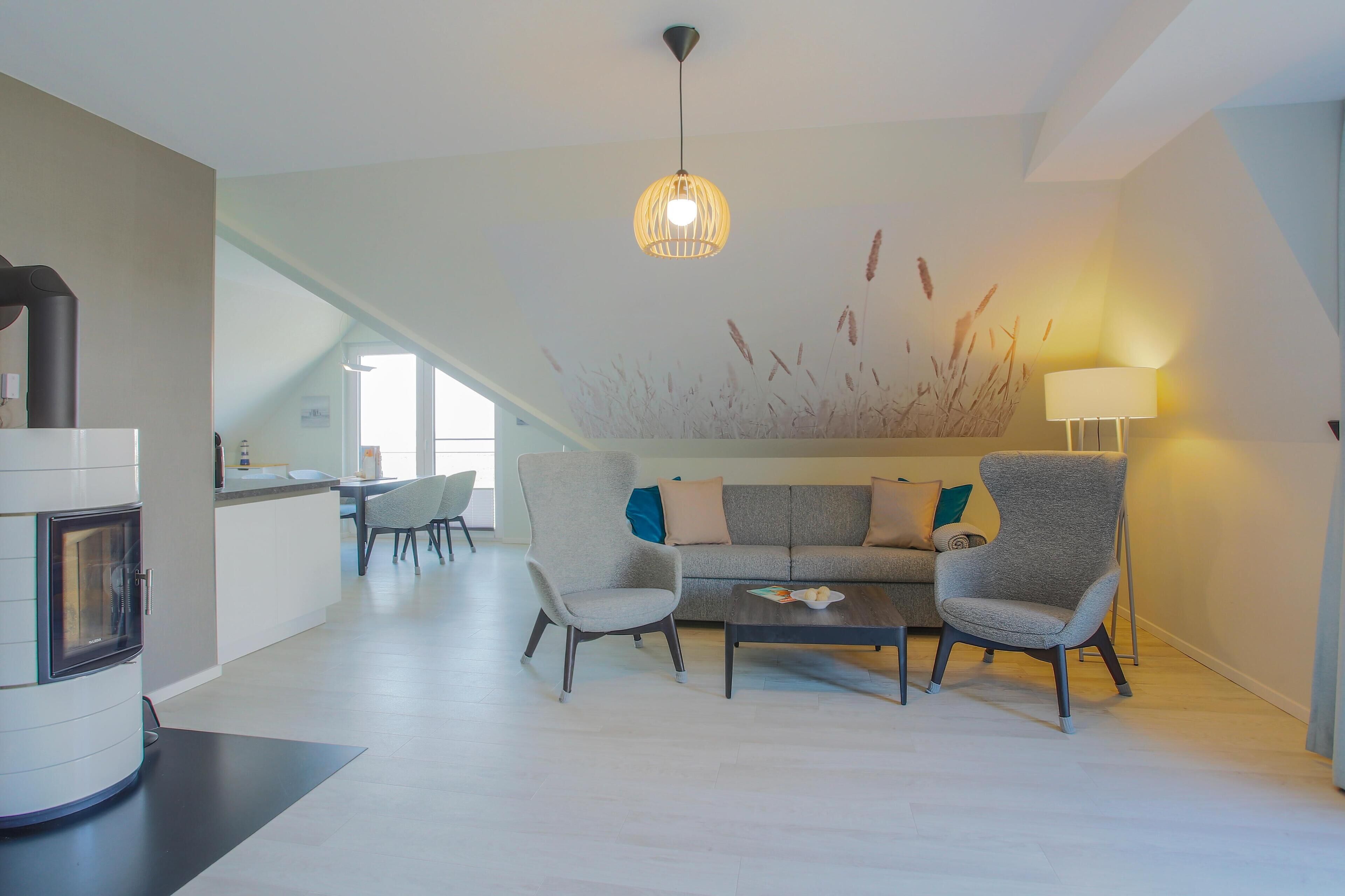 Ein modernes Wohnzimmer mit einer Couch, zwei Sesseln, einem Couchtisch und einem Kamin.