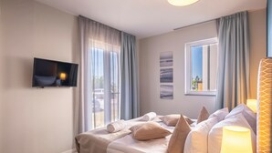 A modern bedroom with a bed, a TV, and a window with curtains. - 5 star vacation apartment "Seestern" between the Baltic Sea and the Bodden (Wustrow)