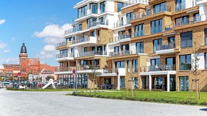A modern apartment building with multiple balconies, large windows, and a brick facade.