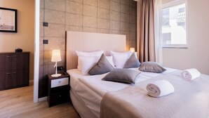 A neatly made bed with pillows and a rolled towel, a bedside table with a lamp, and a view of the outside through a window. - 5 star vacation apartment "Seesinn" in Wustrow on the Baltic Sea (Wustrow)