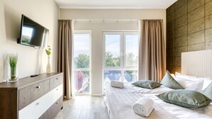 Ett modernt hotellrum med en stor säng, en platt-TV som är monterad på väggen och utsikt över staden genom stora fönster.