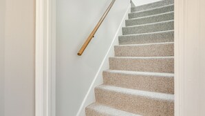 A staircase with a wooden handrail and beige carpeted steps. - 7 Mi to Downtown Minneapolis: Home w/ Fire Pit! (Richfield)