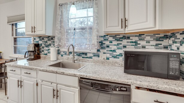 A modern kitchen with white cabinets, a granite countertop, a built-in microwave, and a dishwasher. - 7 Mi to Downtown Minneapolis: Home w/ Fire Pit! (Richfield)