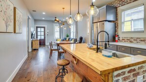 A kitchen with a wooden island, hanging pendant lights, and a brick accent wall. - ~ 2 Mi to Dtwn San Antonio: Comfy Home w/ Yard! (San Antonio)