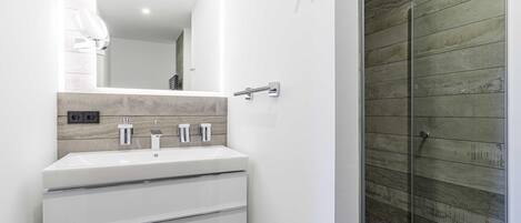 Un baño moderno con un lavamanos blanco, un espejo y un panel de pared de madera.