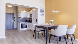 A modern kitchen with white cabinets, a dark countertop, and a dining area with a wooden table and four chairs.