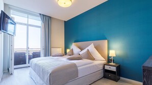 Una camera da letto con un letto grande, una TV fissata al muro e una finestra con tende.