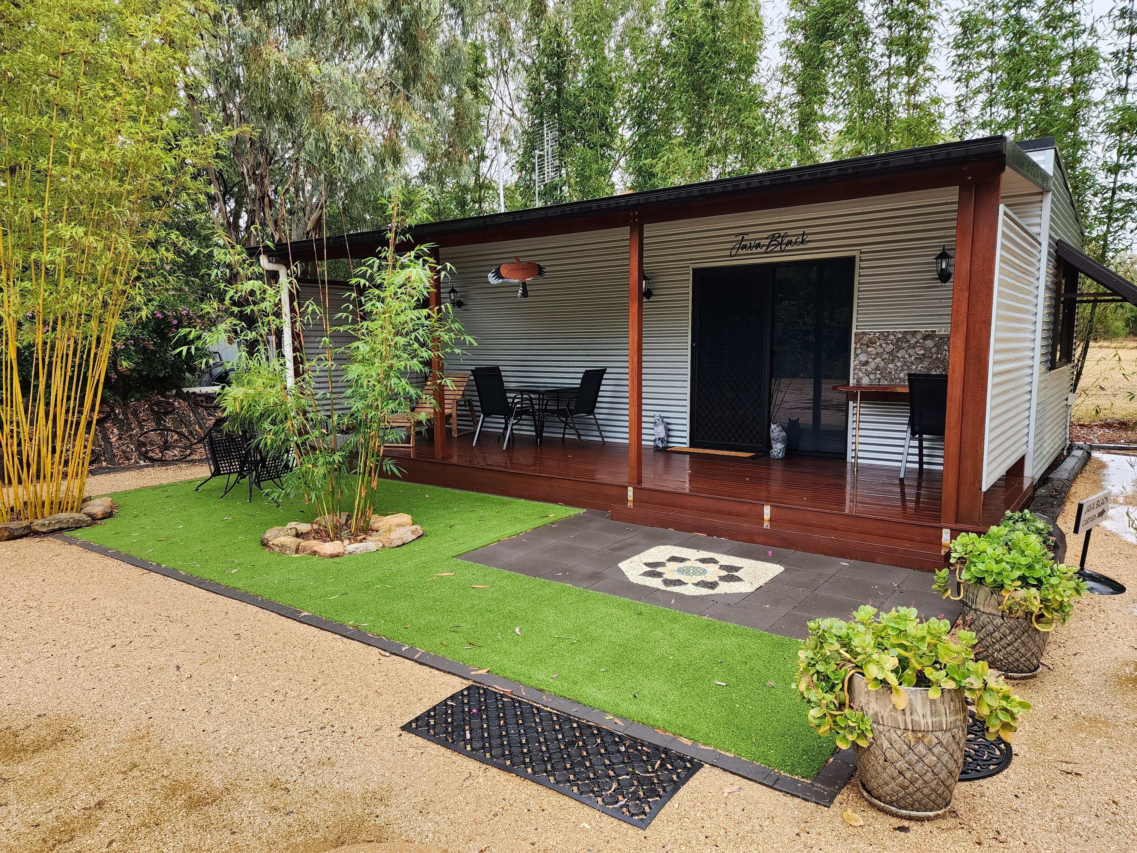 A modern house with a covered patio, a small garden, and a stone wall.