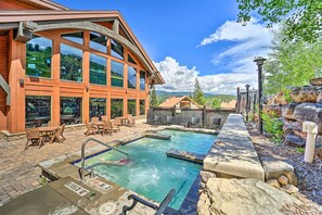 A pool area with a wooden building, outdoor seating, and a view of the mountains. - Skiing & Hiking: Mtn-view Condo in Durango! (Durango)