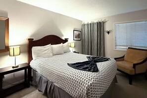 A hotel room with a bed, a chair, a lamp, a picture on the wall, and a window with blinds. - Skiing & Hiking: Mtn-view Condo in Durango! (Durango)
