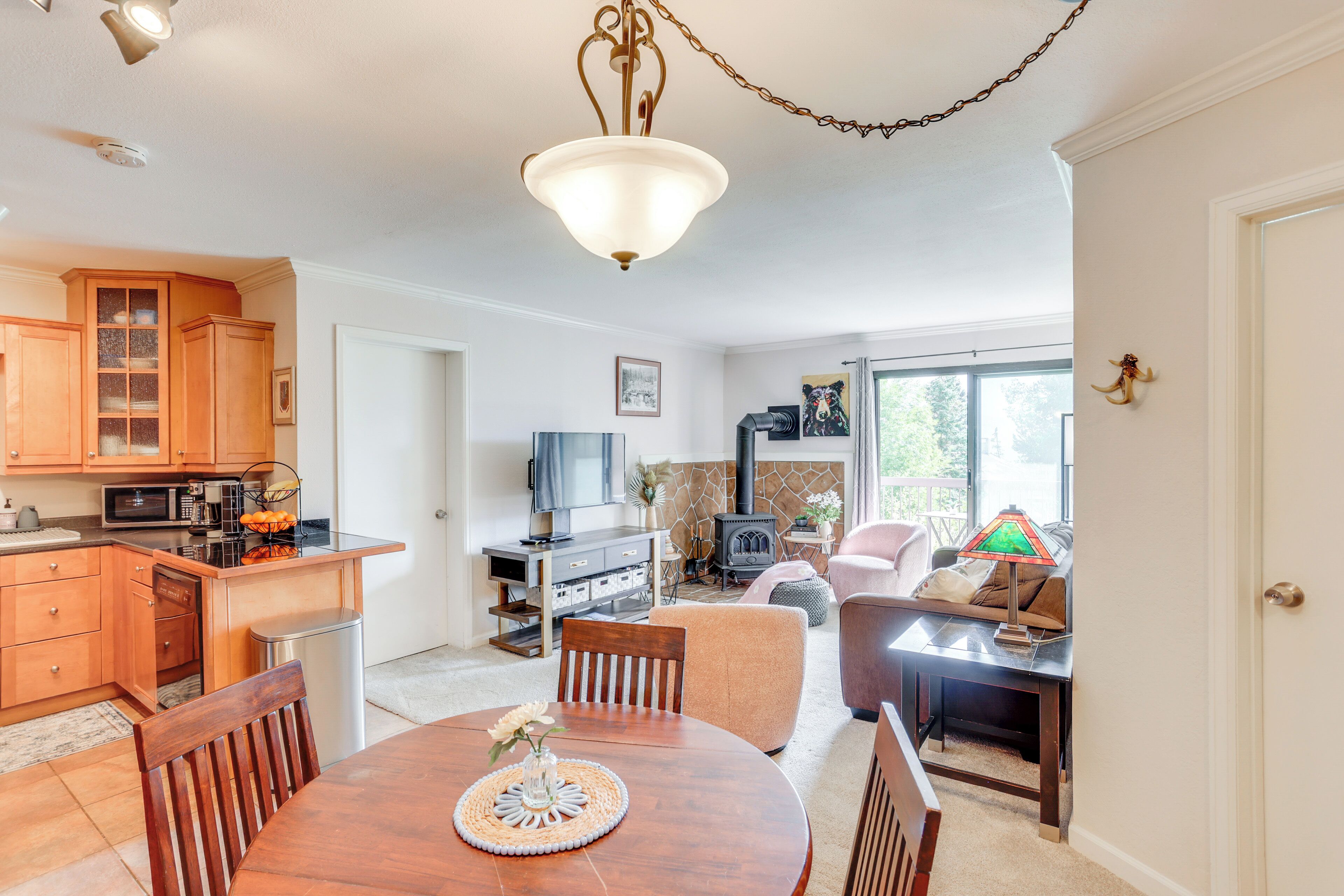 A modern kitchen with wooden cabinets, a dining table with chairs, a TV, and a fireplace.
