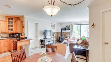 A modern kitchen with wooden cabinets, a dining table with chairs, a TV, and a fireplace.