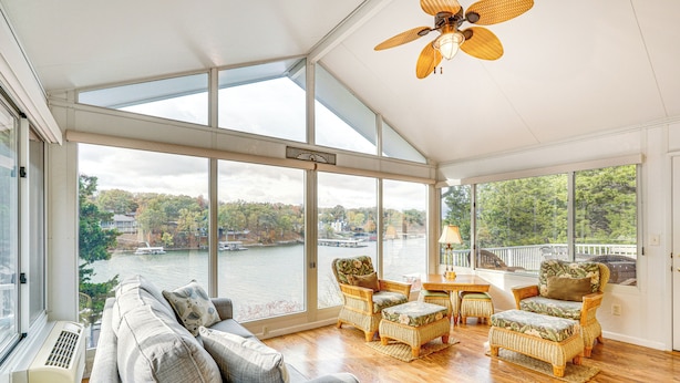 A spacious room with a large window overlooking a river, furnished with a sofa, two wicker chairs, and a small table. - 'the Waterfront Gem' w/ Dock in Osage Beach! (Osage Beach)