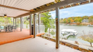 A covered outdoor area with a table and chairs, overlooking a body of water with docks and boats. - 'the Waterfront Gem' w/ Dock in Osage Beach! (Osage Beach)