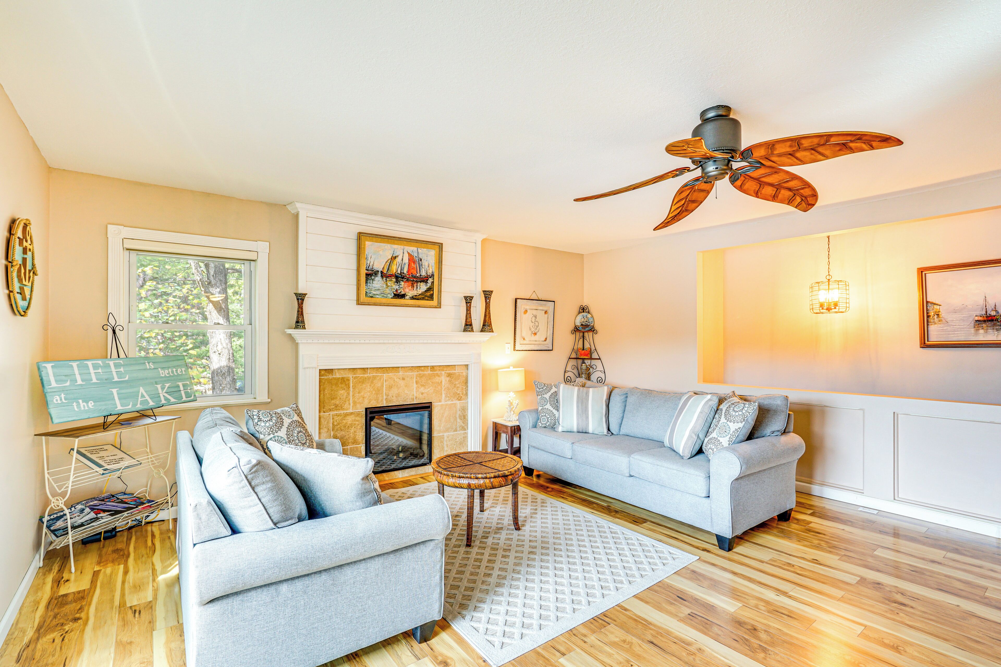 A living room with a fireplace, two sofas, a ceiling fan, and a bookshelf.