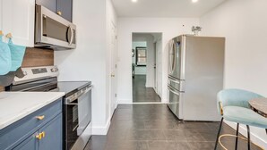 A modern kitchen with dark cabinets, a microwave, oven, and a refrigerator. - 1 Mi to Train Station: Quiet Apartment in Newark (Newark)