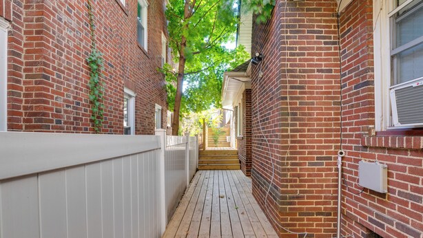 A narrow wooden deck with a white fence on one side and a brick wall on the other. - 1 Mi to Train Station: Quiet Apartment in Newark (Newark)