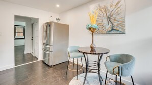 A modern kitchen with a stainless steel refrigerator, a dining table with two chairs, and a wall-mounted painting. - 1 Mi to Train Station: Quiet Apartment in Newark (Newark)
