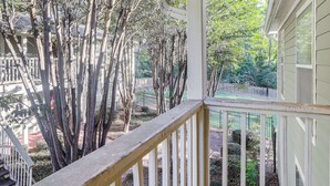 A covered porch with a white railing, overlooking a garden with tall trees and a fence. - Private Deck, 1 Block From The Square (Oxford)