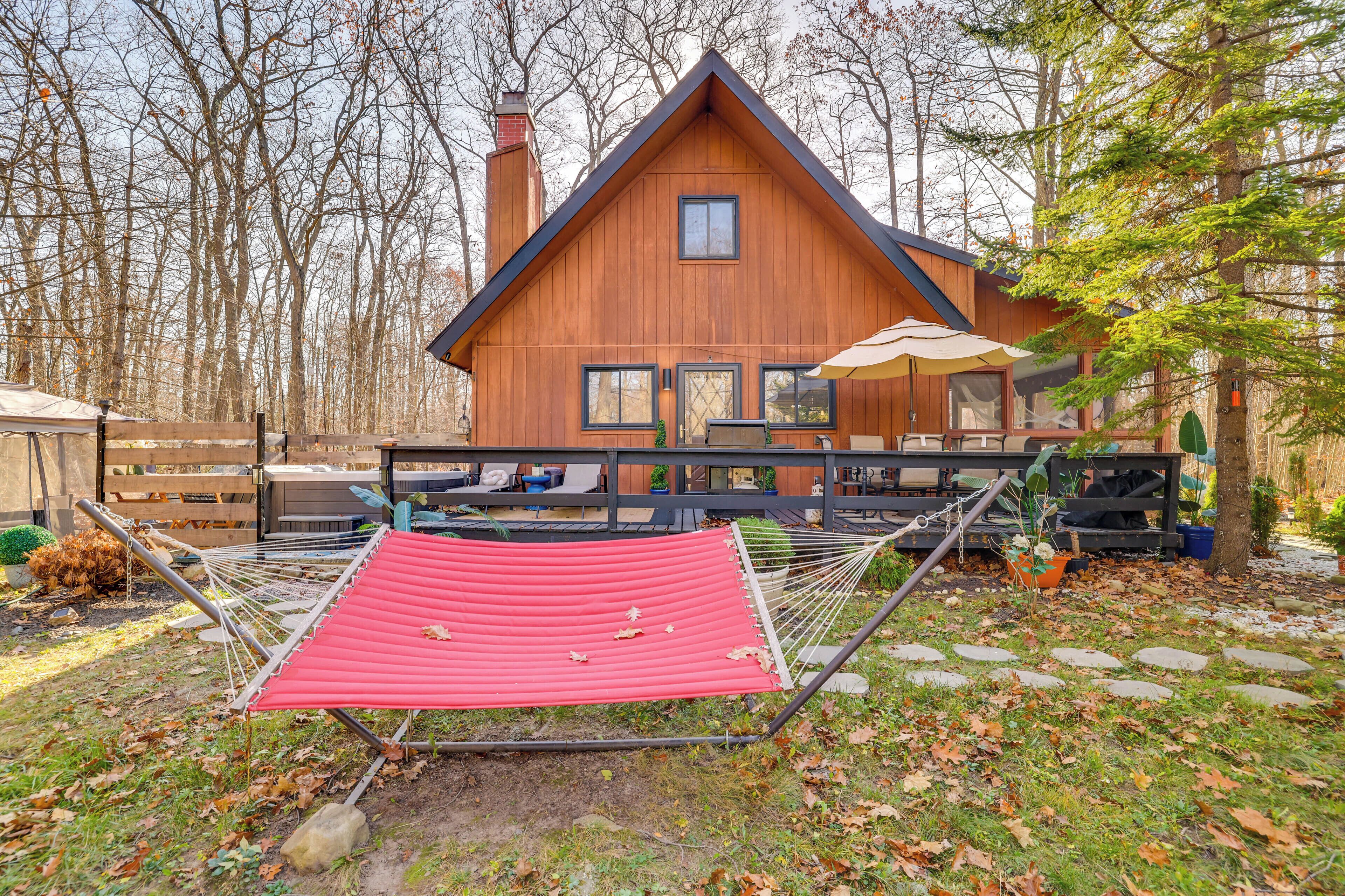 A wooden cabin with a red hammock, stone pathway, and outdoor seating area.