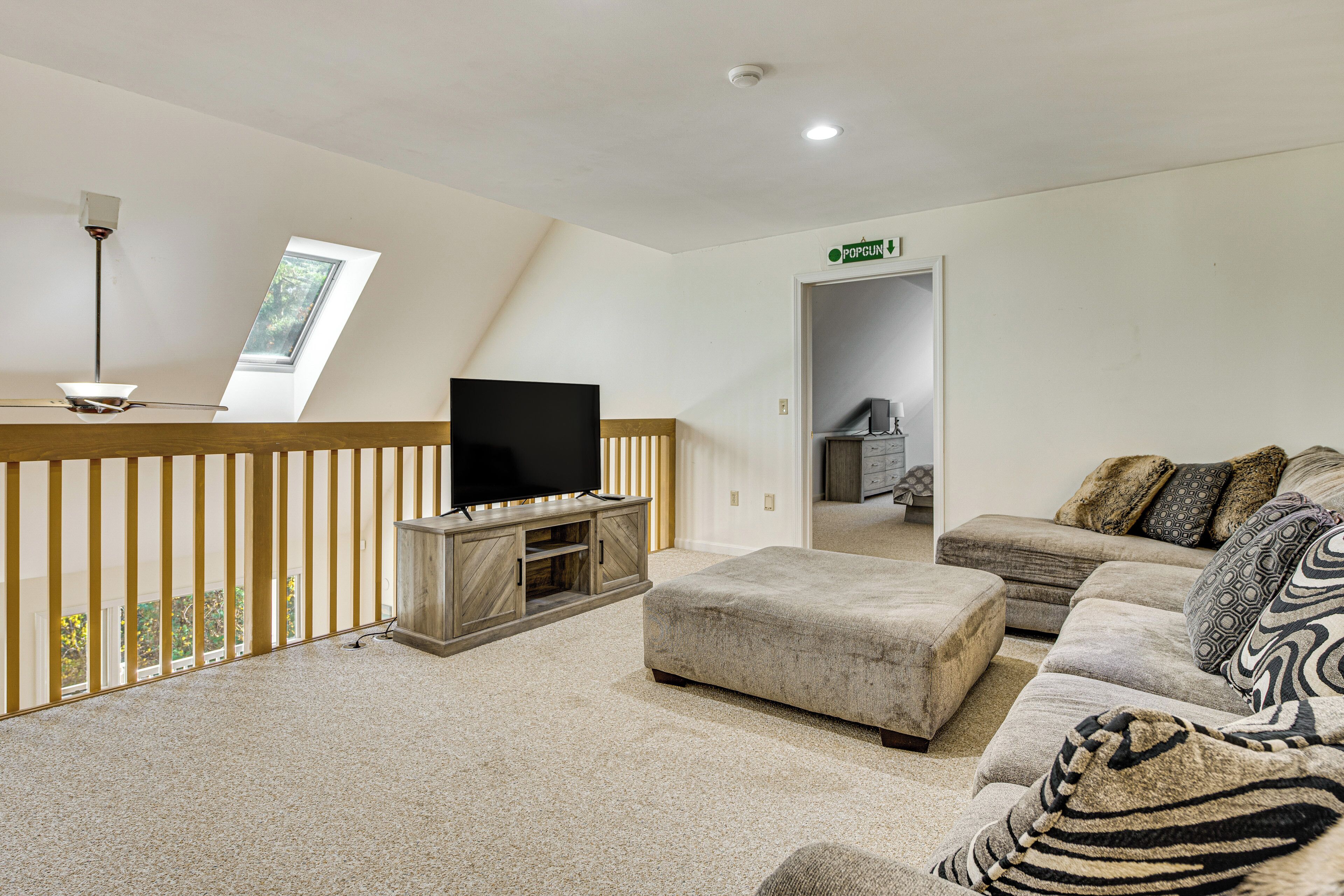 A modern living room with a flat-screen TV, a large sofa, and a wooden entertainment unit.