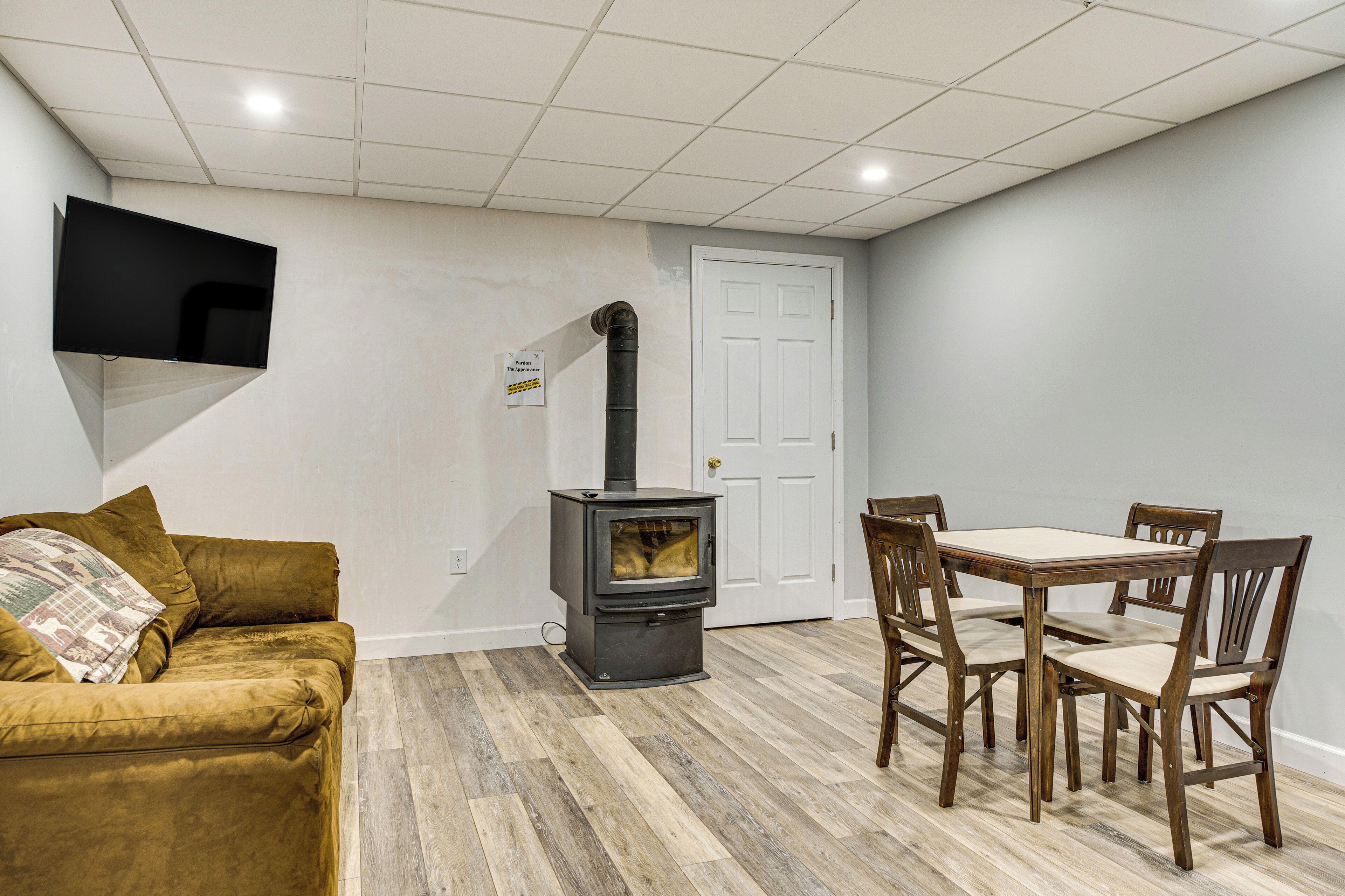A living room with a sofa, a table with chairs, a fireplace, and a television mounted on the wall.