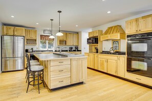 A spacious kitchen with wooden cabinets, stainless steel appliances, and a central island with bar stools.
