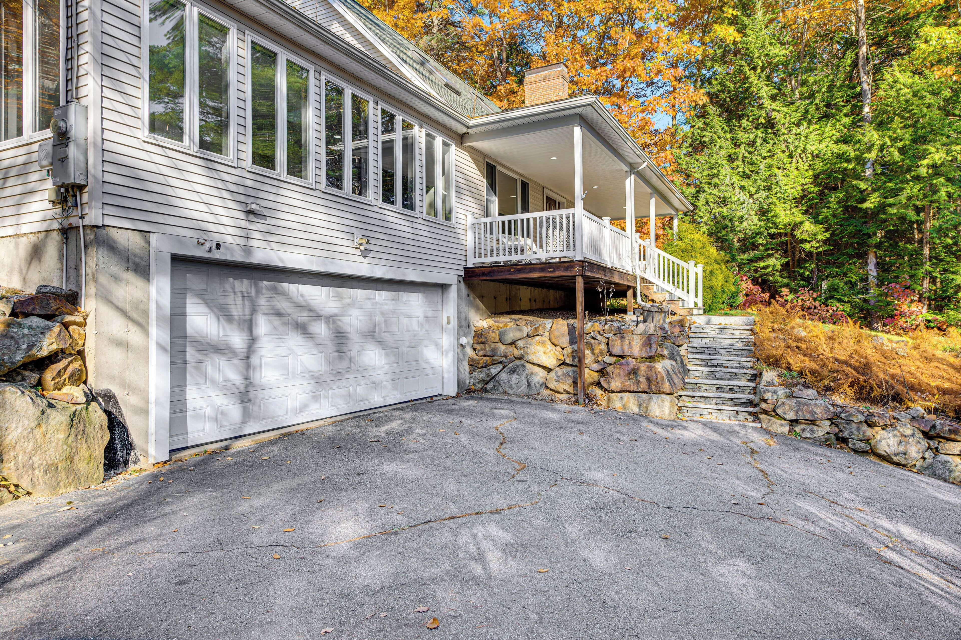 A two-story house with a garage, a covered porch, and a stone staircase leading to the second floor.
