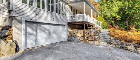 Une maison à deux étages avec un garage, une véranda et un escalier en pierre menant au deuxième étage.