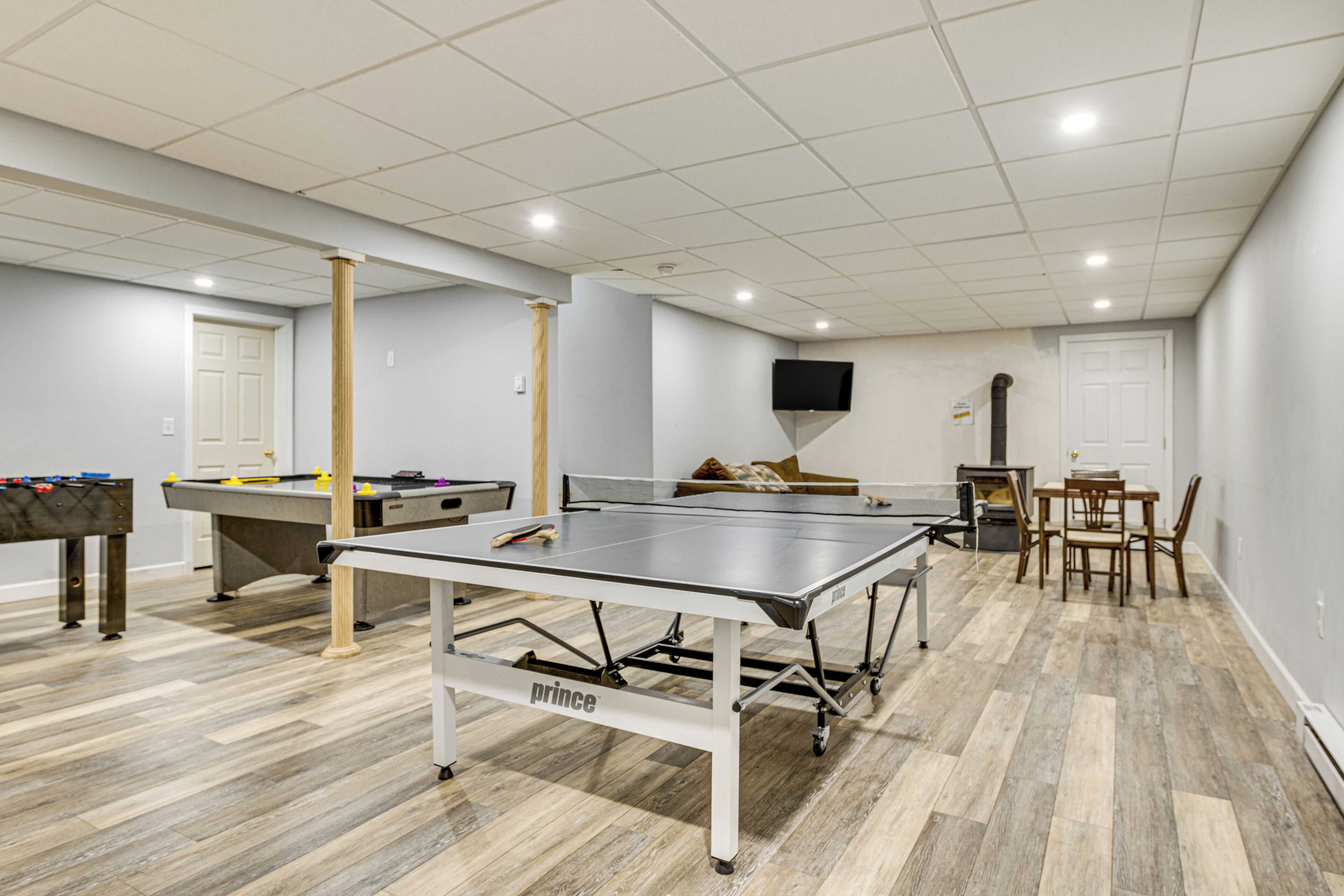 A recreational room with a ping pong table, pool table, and foosball table.