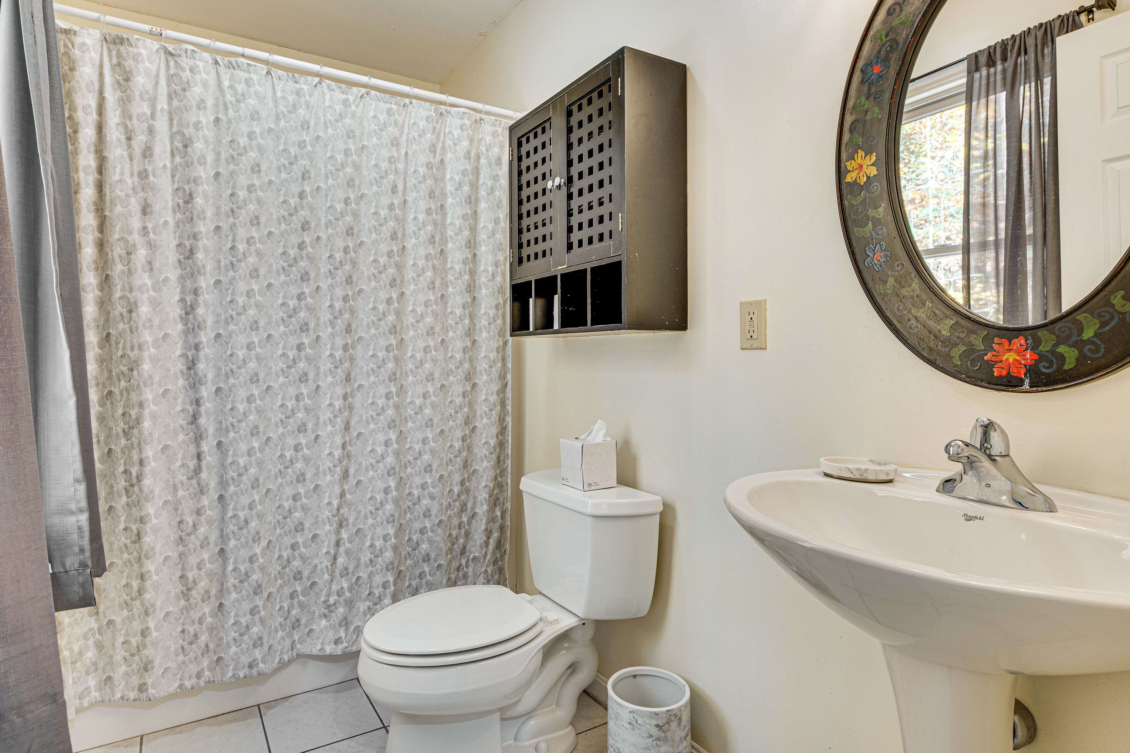 Ein Badezimmer mit Toilette, Waschbecken, Spiegel und Duschvorhang.