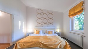 A bedroom with a bed, bedside tables, a window with curtains, and a wall decoration. - Vacation apartment "Fischadler" with terrace in Jabel an der Müritz (Jabel)