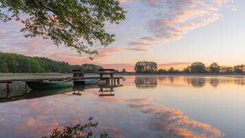 A calm lake with boats docked, surrounded by trees and a clear sky.