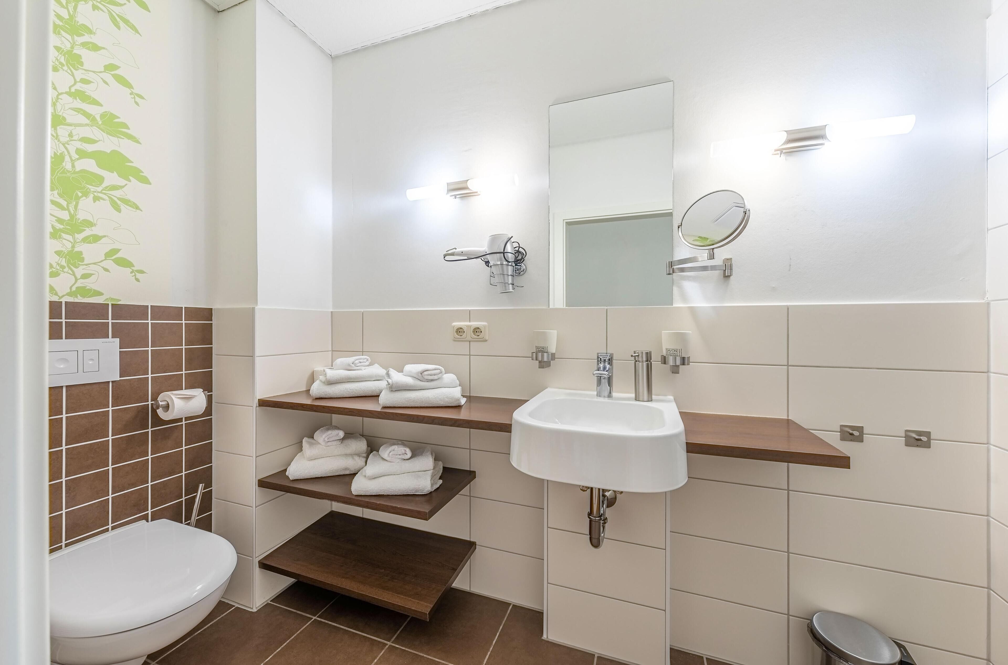 Ein modernes Badezimmer mit Toilette, Waschbecken und Ablageflächen für Handtücher.