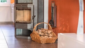 A modern wood-burning stove with a basket of firewood in front. - Vacation apartment "Fischadler" with terrace in Jabel an der Müritz (Jabel)