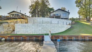 A waterfront property with a dock leading to a house with a large deck and a stone retaining wall. - Dock & Views: Waterfront Home in Wabasha! (Wabasha)
