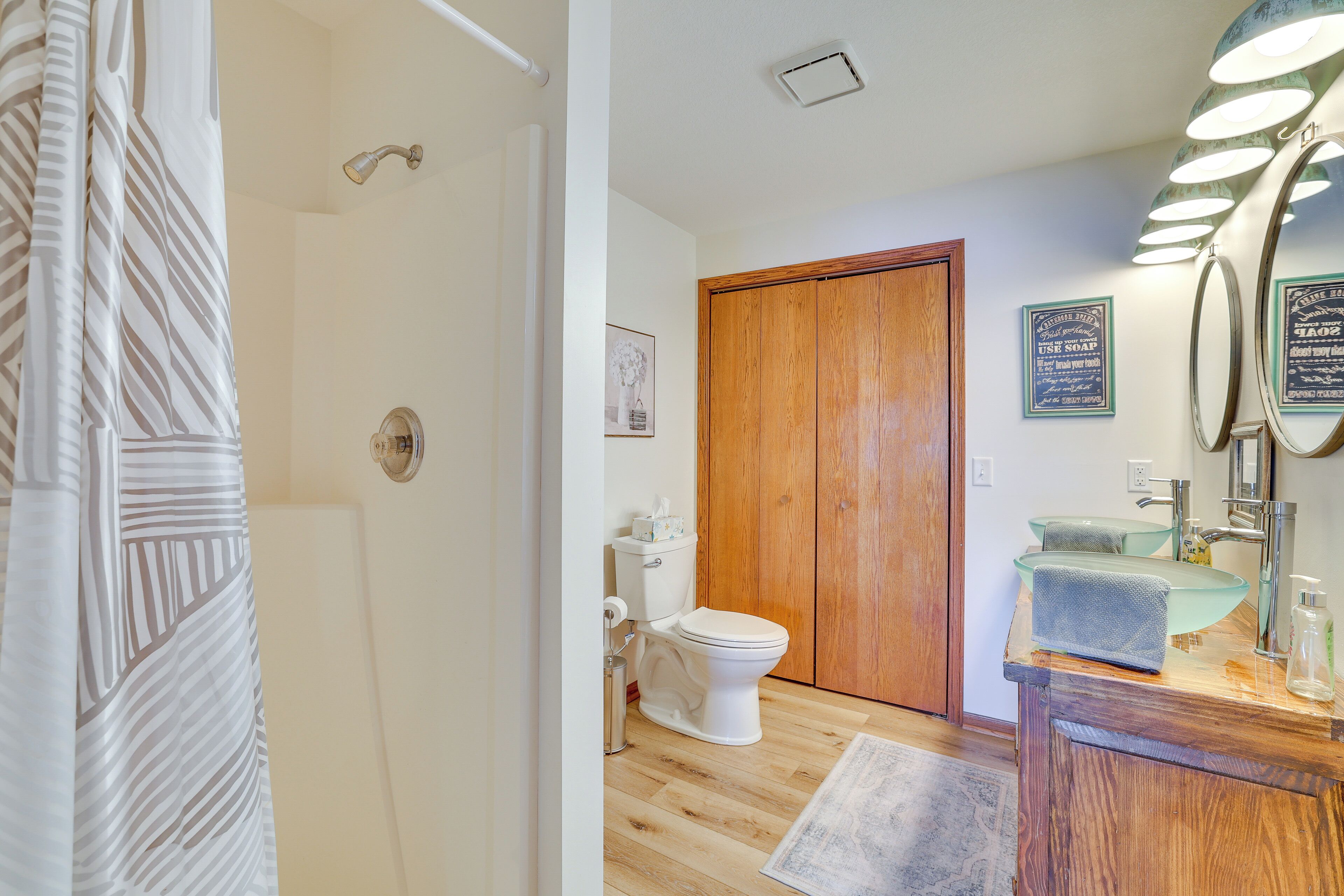 A bathroom with a wooden door, a glass sink, and a toilet.