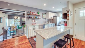 A modern kitchen with a central island, white cabinets, and a stone backsplash. - < 1 Mi to Dtwn: Home w/ Fenced Yard in Boerne! (Boerne)