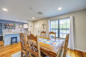 A dining area with a wooden table, chairs, and a window with curtains.