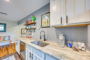 A kitchen with white cabinets, a granite countertop, a stainless steel sink, and a coffee maker.