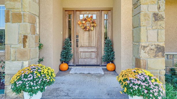 A stone building with a wooden front door, two potted plants with yellow flowers, and two small Christmas trees. - 4 Mi to Dtwn: Home w/ Pool in Stephenville! (Stephenville)