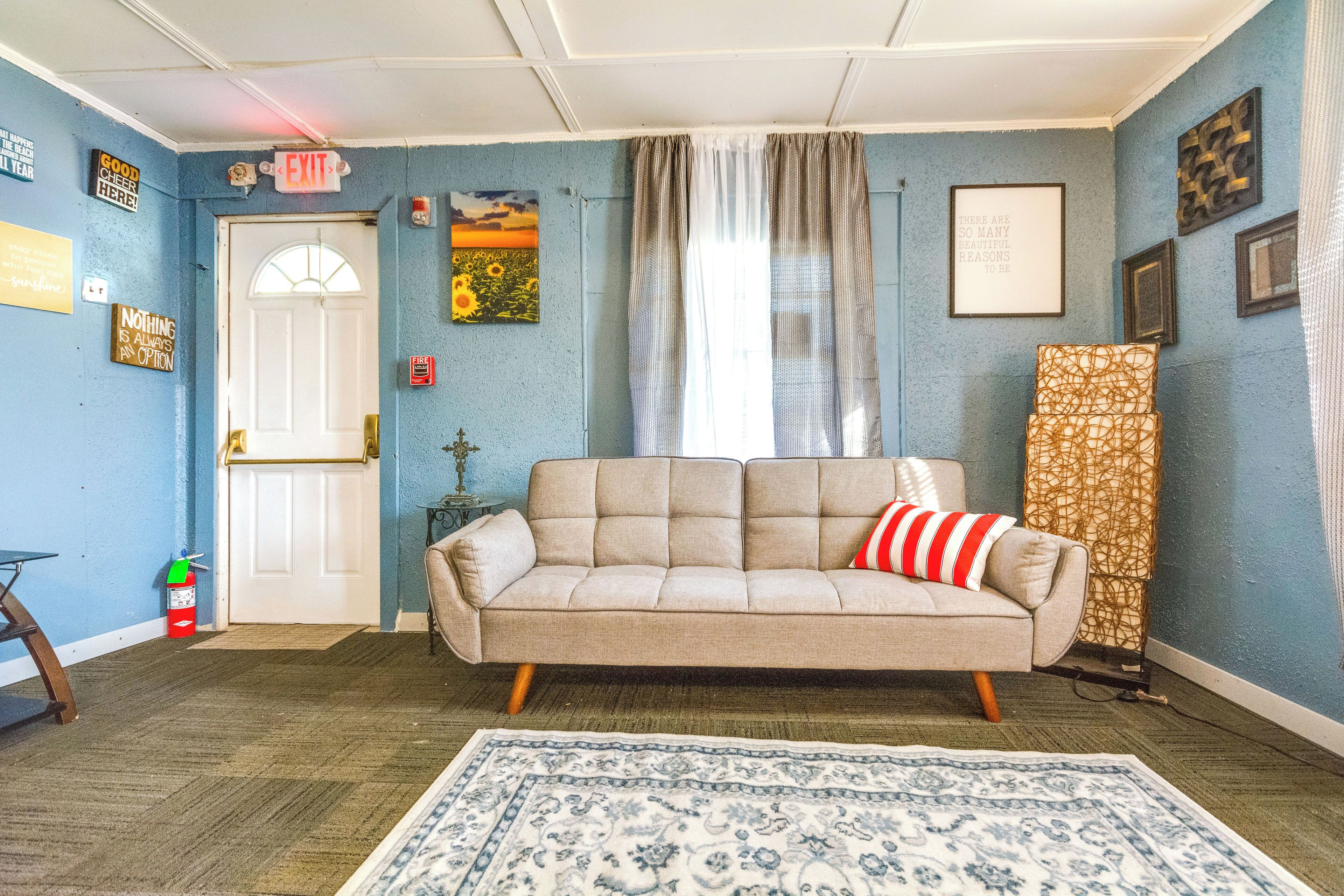 A living room with a beige sofa, a patterned rug, and a door with an EXIT sign.