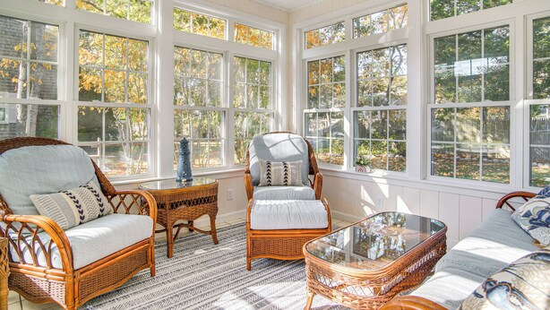 A sunroom with wicker furniture, large windows, and a glass table. - Bike to Private Beach: Cape Cod Escape w/ Sunroom (East Falmouth)